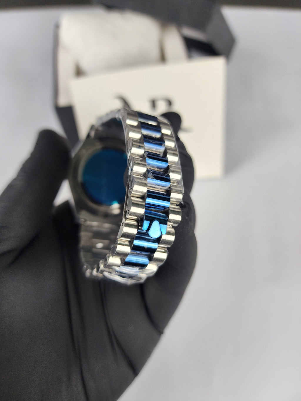 Silver ring with blue stones held by a gloved hand against a blurred background