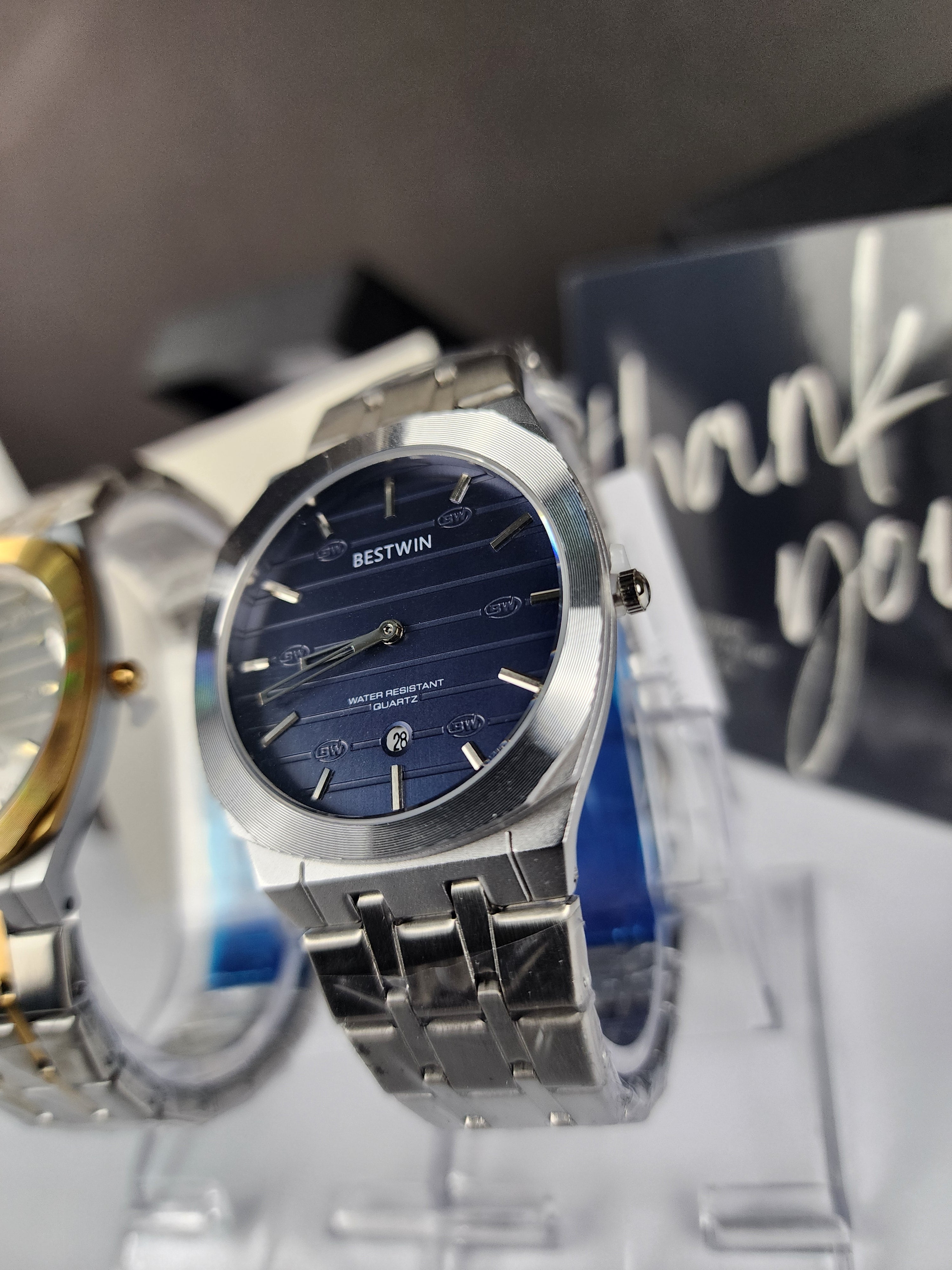 Silver watch with blue face on a reflective surface