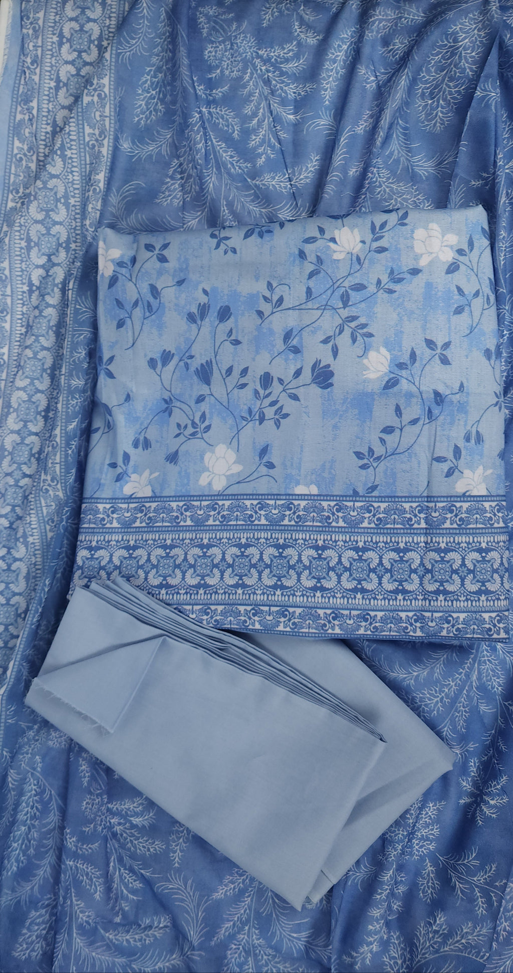 Blue floral fabric with a matching pillow and napkin on a white surface