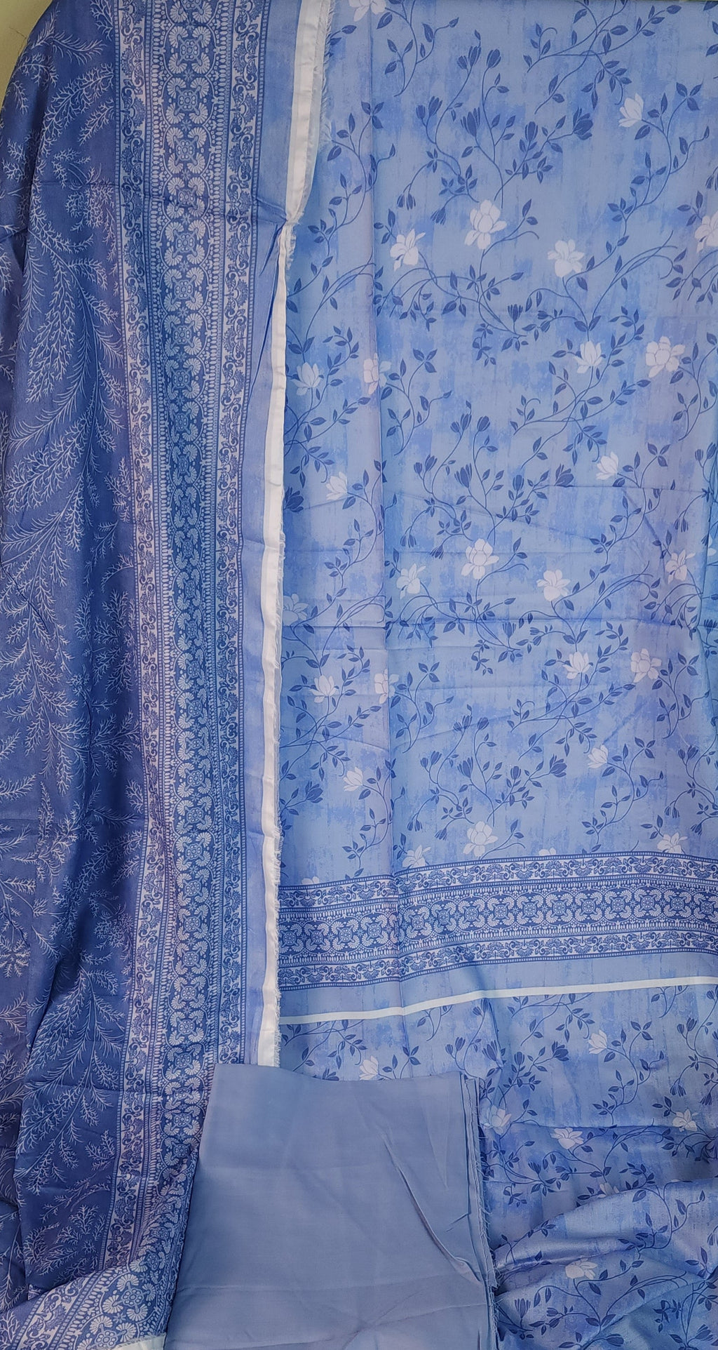 Blue floral dress on a green surface with colorful fabric in the background