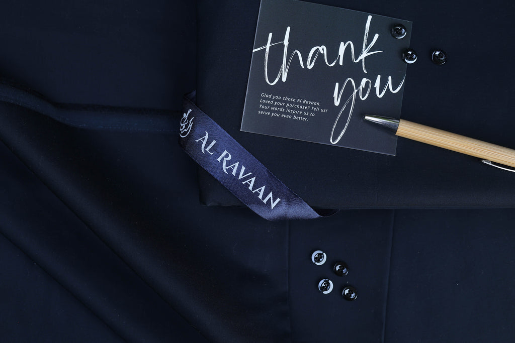 Navy blue suit with a 'thank you' card and pen on a dark background