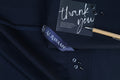 Navy blue suit with a 'thank you' card and pen on a dark background