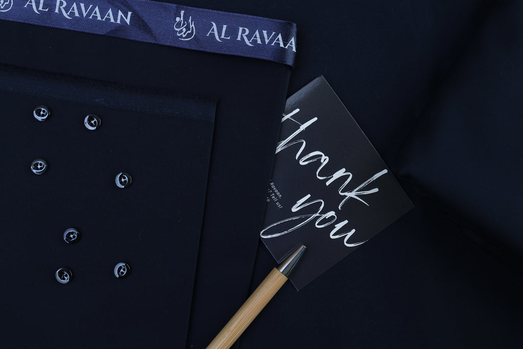 Navy blue shirt with a 'thank you' card and pen on a dark background