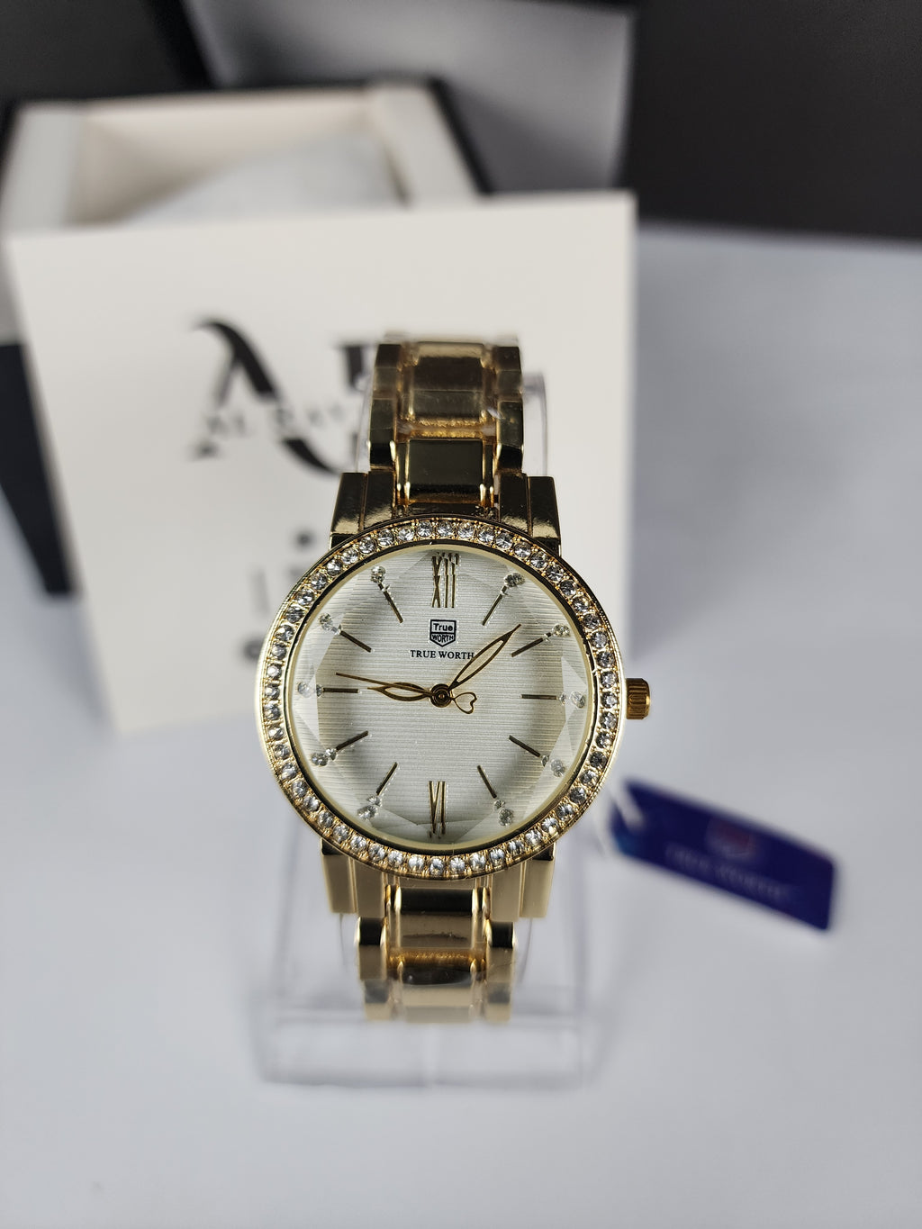 Gold wristwatch with diamond-like accents on a white box